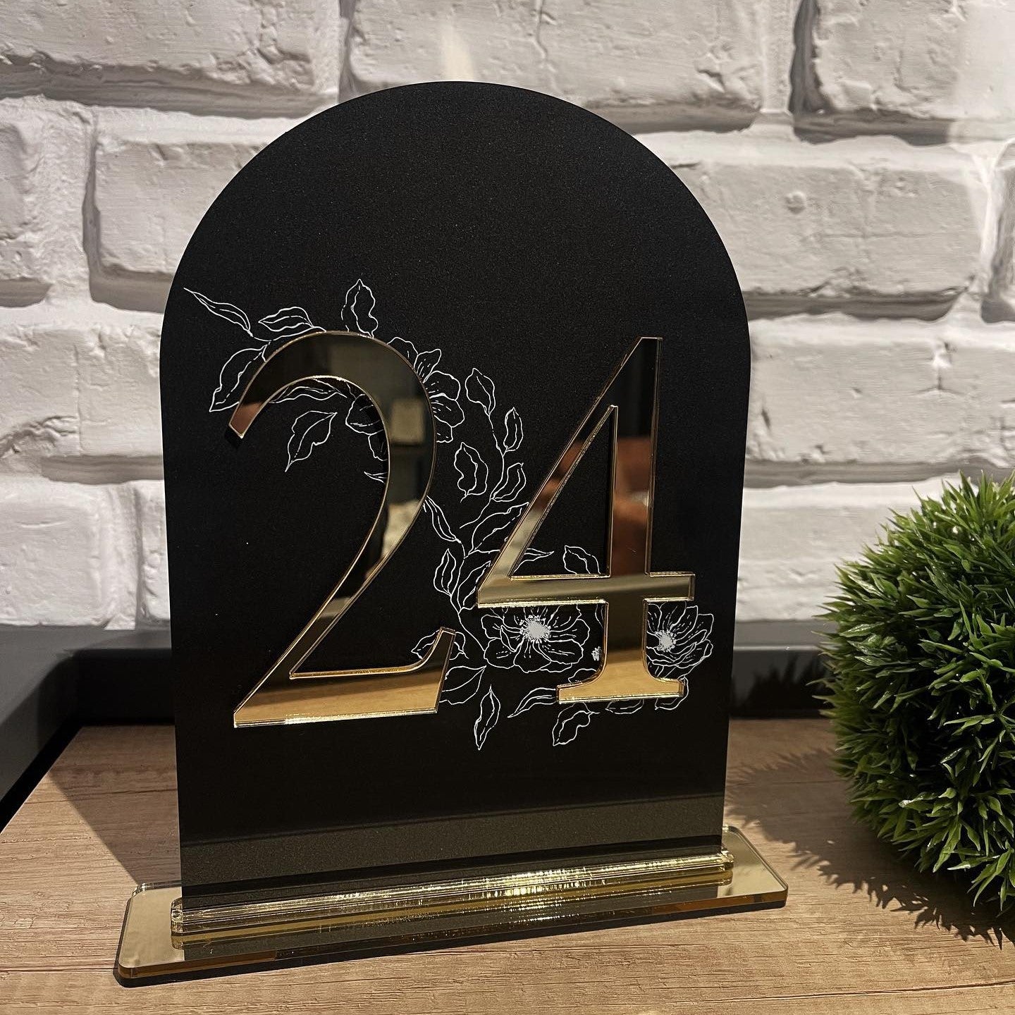 Număr de masă din acril negru cu detalii aurii și design floral pe fundal, realizat de Diandra Events pentru decor elegant de nuntă