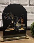 Număr de masă din acril negru cu detalii aurii și design floral pe fundal, realizat de Diandra Events pentru decor elegant de nuntă
