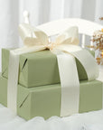 Cutii cadou verde salvie decorate cu panglică satin ivory lată, aranjate elegant pentru evenimente speciale – Diandra Events