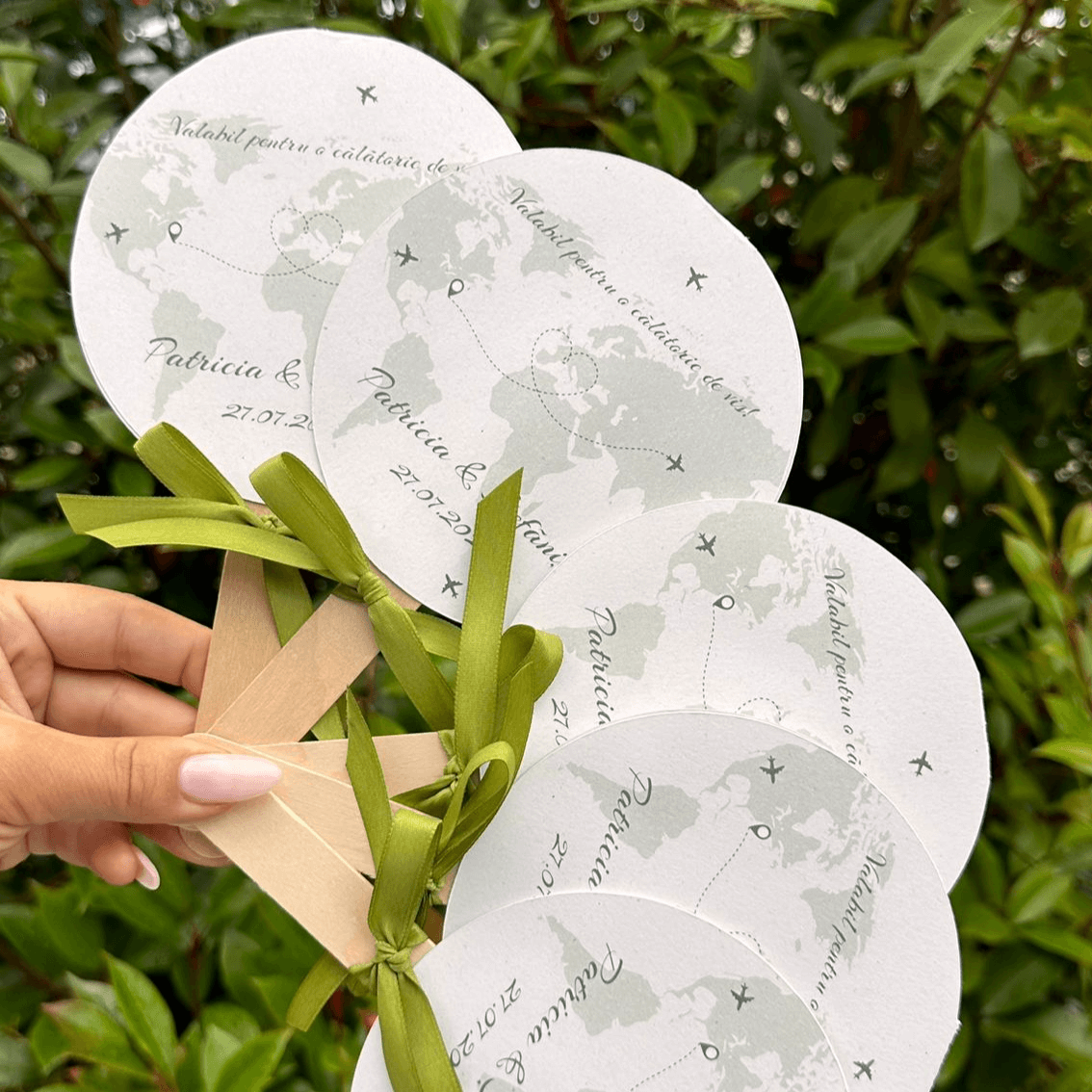 Evantai de nuntă tematică destinații Diandra Events, design cu hartă lumii și trasee de călătorie, fundă satinată verde, personalizat cu numele mirilor și data nunții.