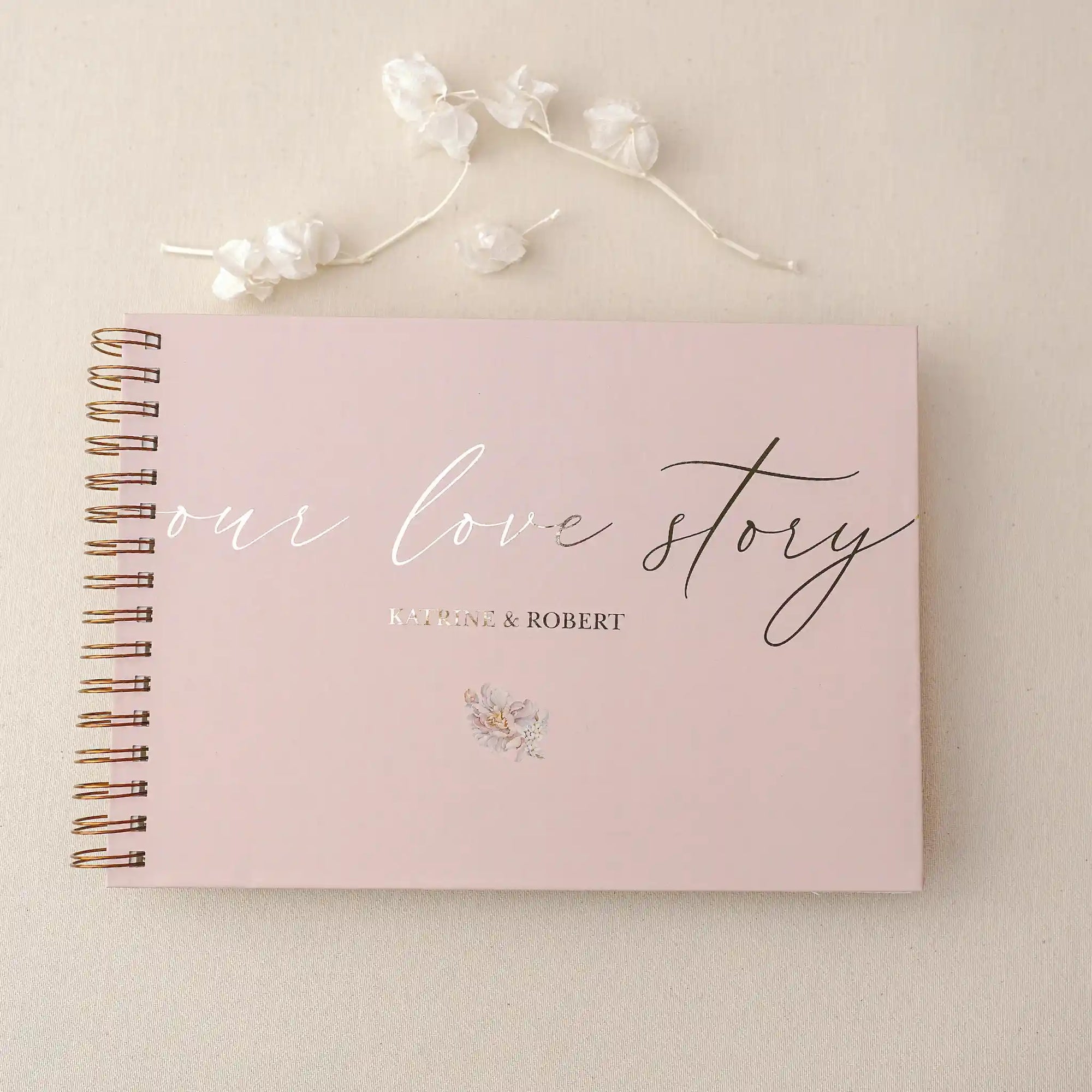 Guest book personalizat folio cu text „Our Love Story”, copertă roz și spirală aurie, ideal pentru nuntă sau aniversare realizat de Diandra Events