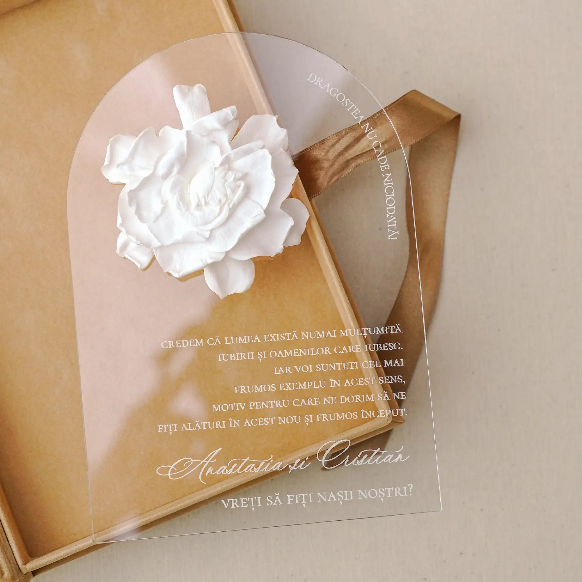 Invitație nași plexiglas elegantă, cu floare chiroginată albă și text personalizat gravat, așezată într-o cutie din catifea premium