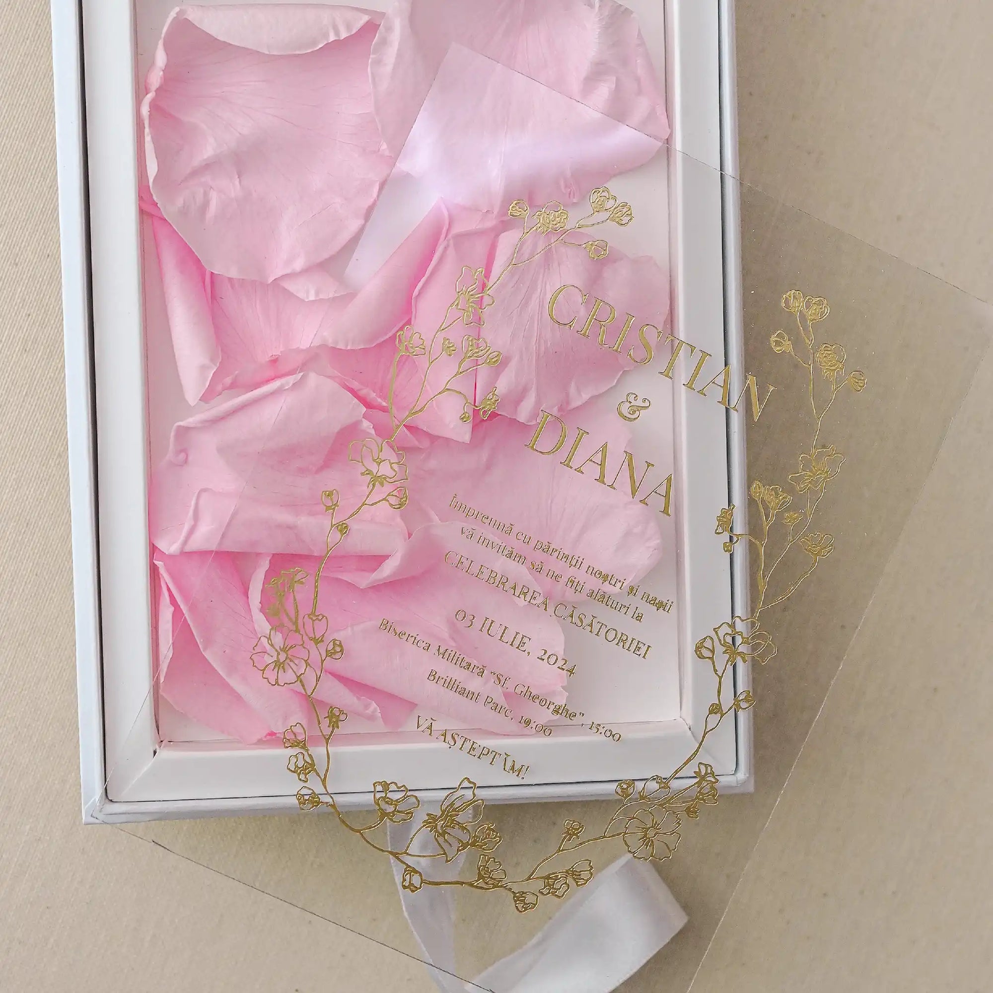 Invitație nași acrilică cu flori aurii gravate și petale roz, prezentată într-o cutie albă elegantă