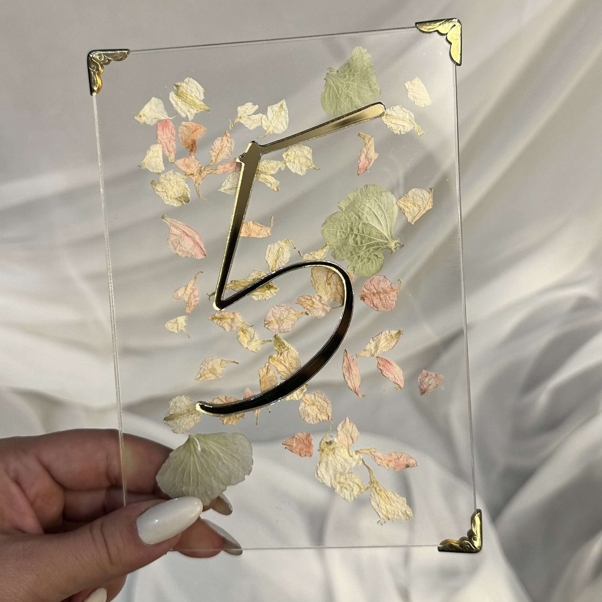 Număr de masă pentru nuntă din plexiglas transparent cu flori uscate și număr în relief auriu, design elegant realizat de Diandra Events