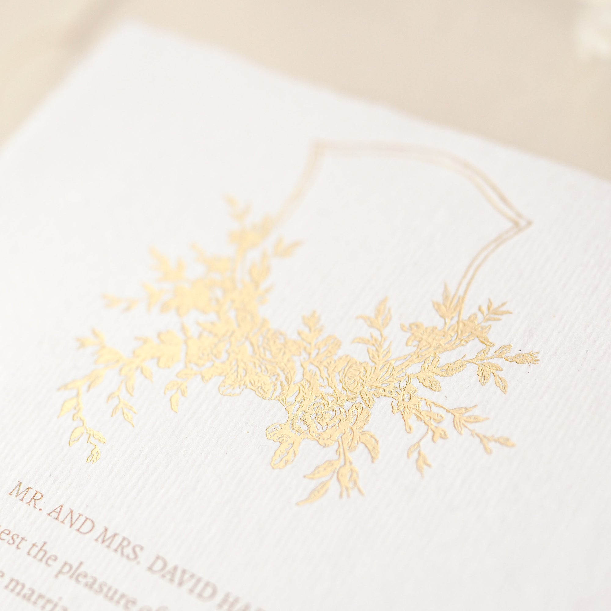 Detaliu embosare florală cu folie aurie pe hârtie manuală pentru invitații de nuntă elegante – design Diandra Events

