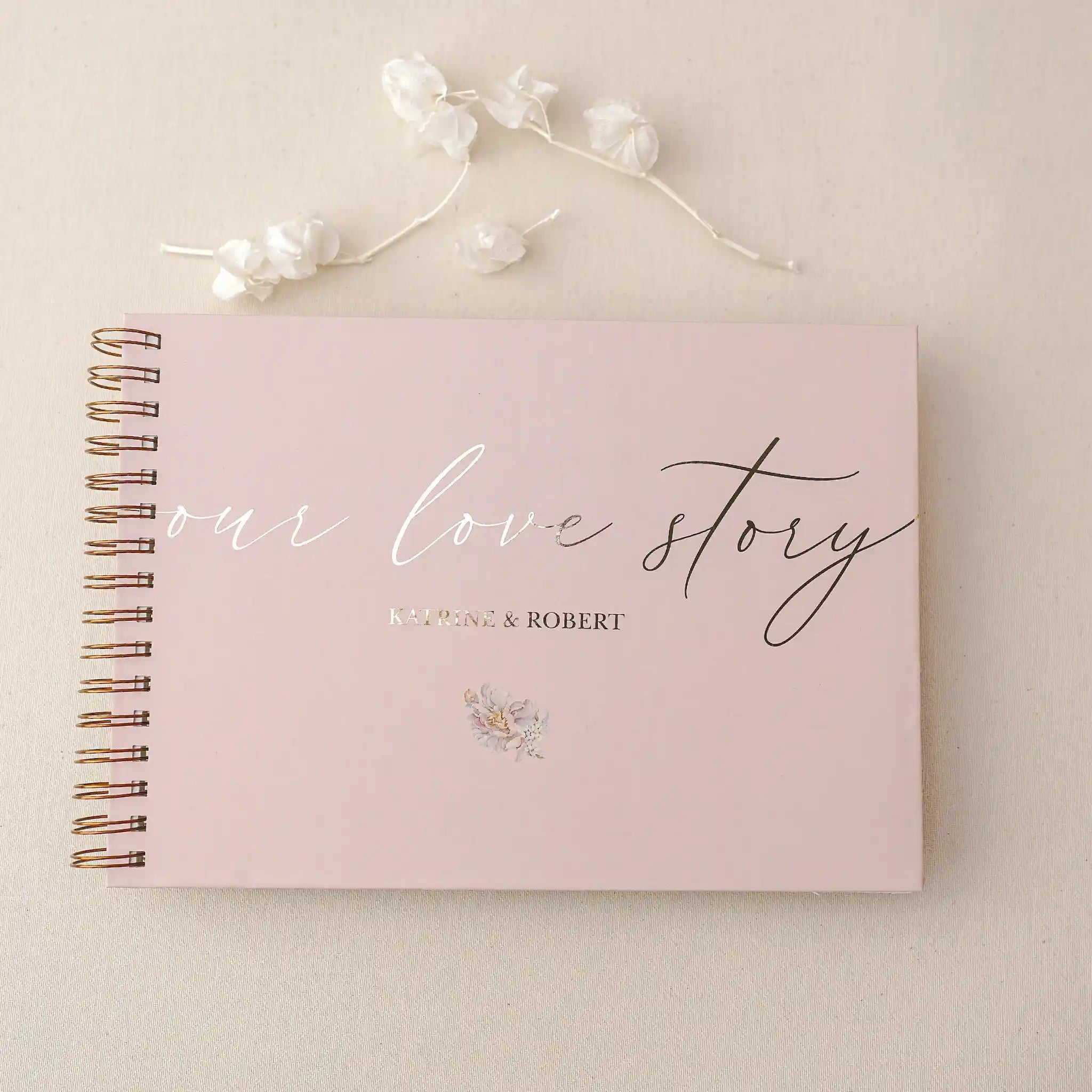 Guest book personalizat folio cu text „Our Love Story”, copertă roz și spirală aurie, ideal pentru nuntă sau aniversare realizat de Diandra Events